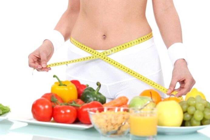 گروسری کے پس منظر کے خلاف کمر کی پیمائش کرنے والی لڑکی